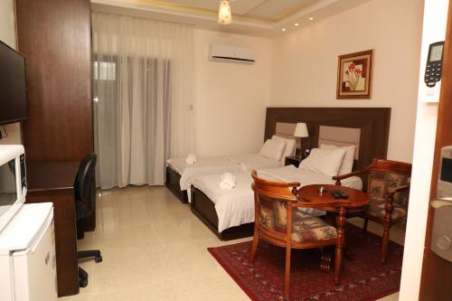 a hotel room with a bed and a table and a desk at AlQimah Hotel Apartments in Amman