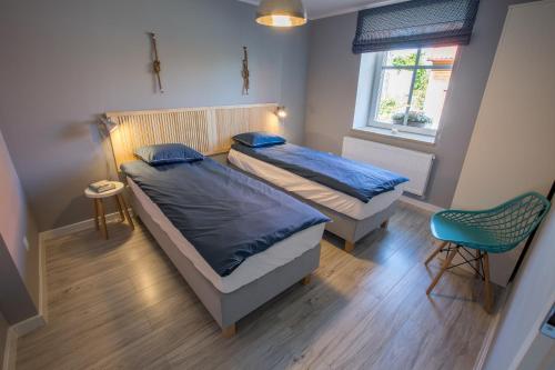 a bedroom with two beds and a chair and a window at Apartament na Cysterskim Szlaku in Starzyno