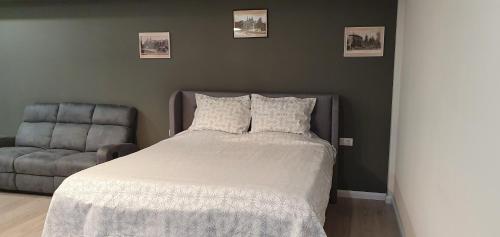 a bedroom with a bed and a chair and pictures on the wall at Yla Studio- Piatra Neamț in Piatra Neamţ