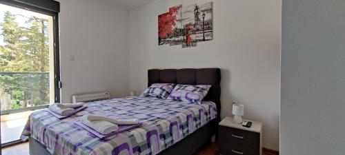 um quarto com uma cama com lençóis roxos e uma janela em Deluxe apartment Sunrise Trebinje em Trebinje