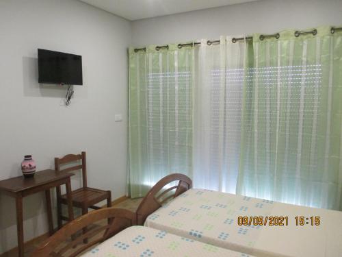 a bedroom with a bed and a television and a table at Casa de Campo Sonhos D'ouro in Ribeira