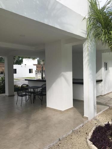 a white house with a patio with chairs and a table at Corte de Los Angeles in Puerto Morelos