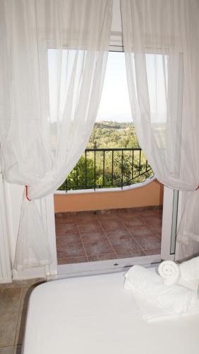 a bedroom with a bed and a window with a balcony at Quality Suite, Tranquility, Sea Views, Breeze in Agios Gordios
