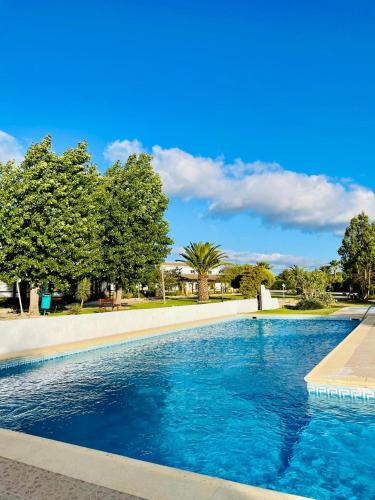 a swimming pool with blue water in a park at Hotel Rural A Coutada - Peniche in Atouguia da Baleia