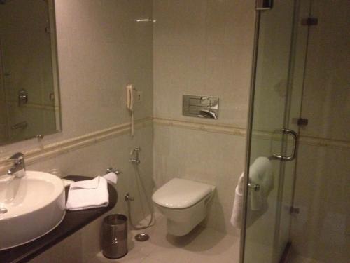 a bathroom with a toilet and a sink and a shower at Mastiff Grand Manali Resort in Manāli