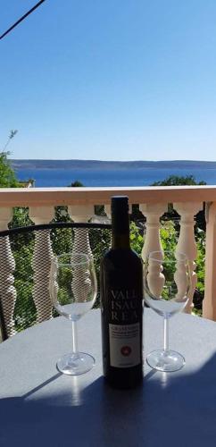 a bottle of wine sitting on a table with two wine glasses at Apartment Ante and Dijana in Starigrad-Paklenica