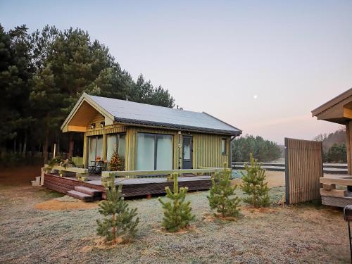 a small yellow house with trees in front of it at Green Valley vacation homes in Žocenes Ciems