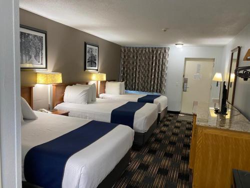 a hotel room with three beds and a television at Cedar Cove in Sandusky