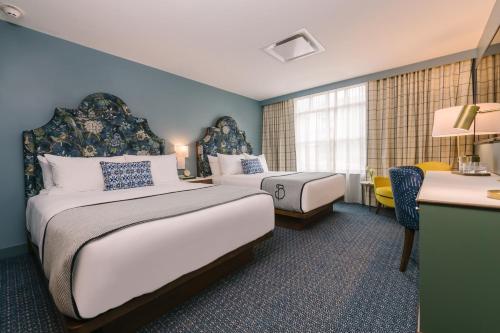 a hotel room with two beds and a desk at The Bradley in Fort Wayne