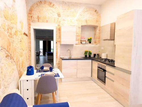 a kitchen with white cabinets and a table and chairs at Home Giulia Best Vacation Ever in Cagliari