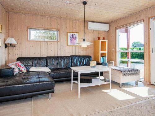 6 person holiday home in Hejls في Hejls: غرفة معيشة مع أريكة جلدية سوداء وطاولة