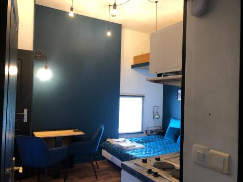 une petite chambre avec une table et un mur bleu dans l'établissement Nouveau L'escapade Chinonaise, à Chinon