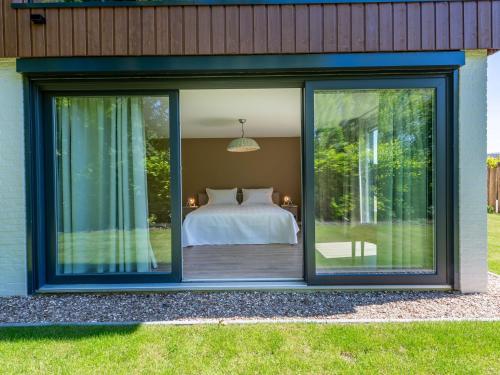 een slaapkamer met een bed en glazen schuifdeuren bij Lovely holiday home in a quiet location, equipped with every comfort in Kamperland