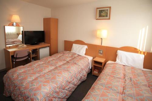 ein Hotelzimmer mit 2 Betten und einem Schreibtisch in der Unterkunft The Celecton Takamatsu in Takamatsu