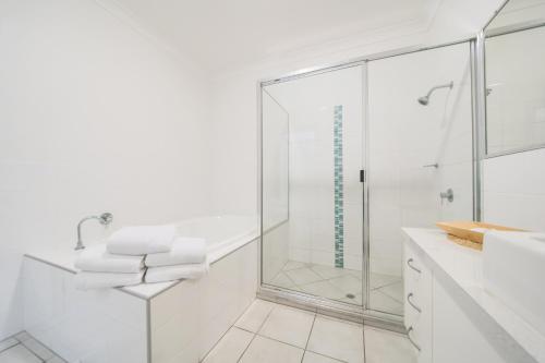 a white bathroom with a shower and a sink at The Coast Motel in Yeppoon