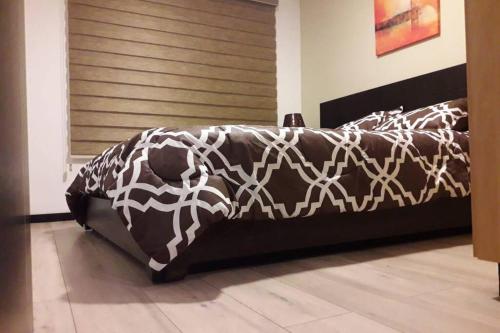 a black bed with a brown and white comforter at Hermoso apartamento en condominio La Victoria in Cuenca