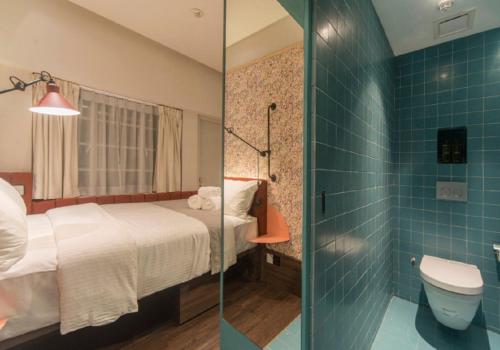 ein Bad mit einem Bett und einem WC in einem Zimmer in der Unterkunft The Great Madras by Hotel Calmo in Singapur