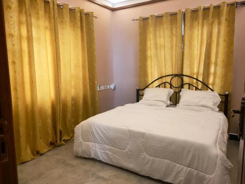 um quarto com uma cama e cortinas amarelas em Heavenly ApHEARTment with backyard swimming pool em Dodoma