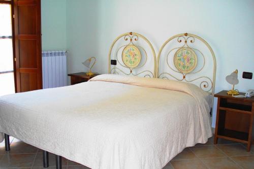 ein Schlafzimmer mit einem weißen Bett und zwei Nachttischen in der Unterkunft Albergo La Casa Nel Bosco in Col Sant'Angelo