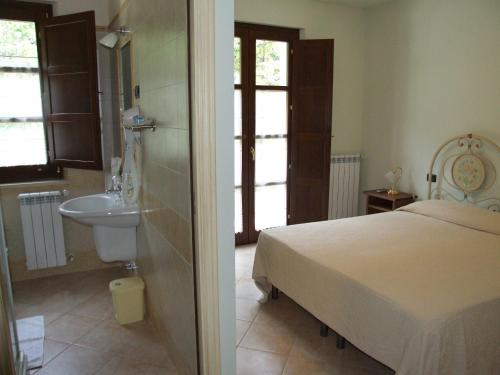 ein Schlafzimmer mit einem Bett und einem Waschbecken sowie ein Badezimmer in der Unterkunft Albergo La Casa Nel Bosco in Col Sant'Angelo