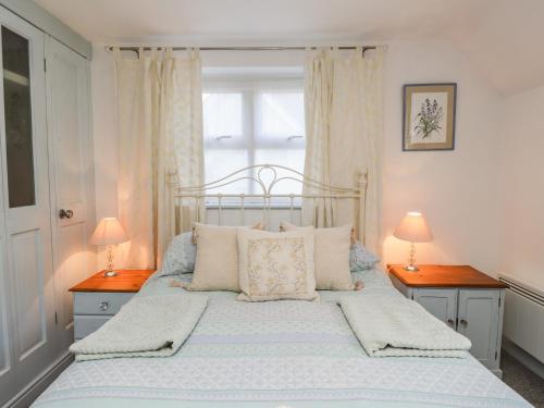 a bedroom with a bed with two lamps and a window at Wood Glen Cottage in Dallington