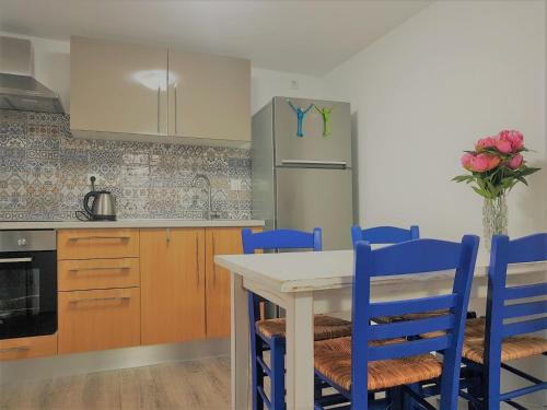 a kitchen with a table with blue chairs and a refrigerator at Spitaki Apartments Potos in Potos