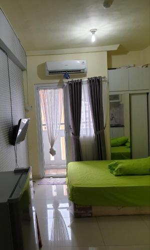 1 dormitorio con cama, ventana y TV en Properti9 at Apartemen Green Pramuka, en Yakarta