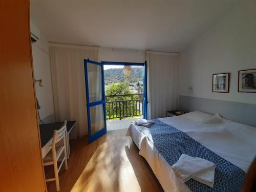 a bedroom with a bed and a large window at Hylatio Tourist Village in Pissouri