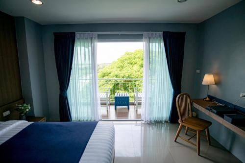 Schlafzimmer mit einem Bett, einem Schreibtisch und einem Fenster in der Unterkunft The Cavalli Casa Resort in Phra Nakhon Si Ayutthaya