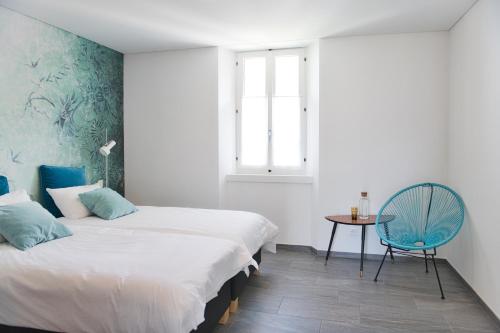 a bedroom with two beds and a blue chair at Salotto Brè - Bed & Breakfast charming rooms in Lugano