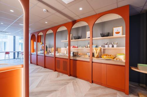 une cuisine avec des armoires orange dans un restaurant dans l'établissement ibis Styles Le Mans Gare Sud, au Mans
