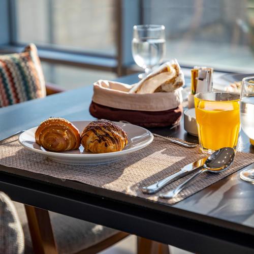 a table with a plate of pastries and a glass of orange juice at Horizon Hotel in Al Başrah