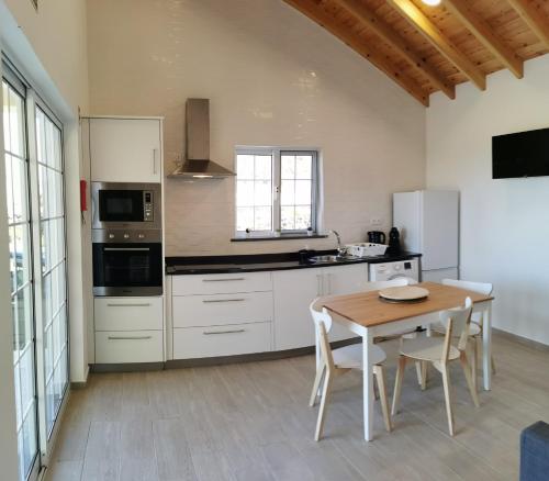 a kitchen with white cabinets and a wooden table at Houses of Eira Velha in Fajã do Ouvidor