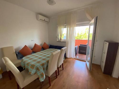 una sala da pranzo con tavolo, sedie e una finestra di Renic Apartments a Nin