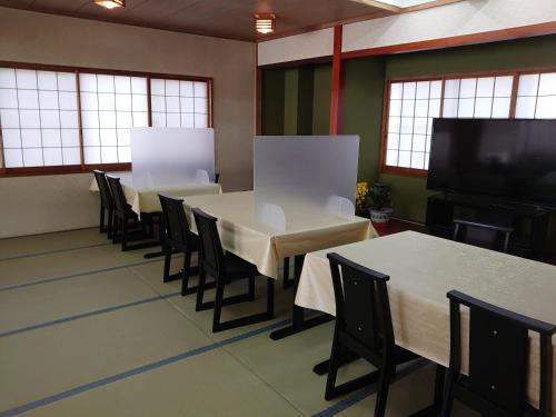 a dining room with tables and chairs and a flat screen tv at Resort Inn Fujihashi in Fujikawaguchiko