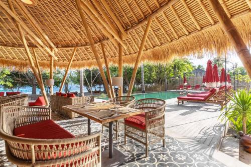 a patio with a table and chairs and a pool at Amahelia Luxury Resort & Restaurant - Gili Asahan in Gili Asahan