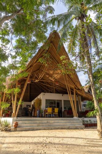 a house with a thatched roof on the beach at Amahelia Luxury Resort & Restaurant - Gili Asahan in Gili Asahan