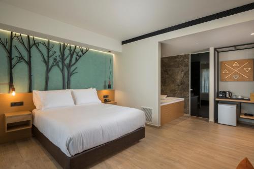 a bedroom with a bed and a bathroom with a tub at Hyperion City Hotel & Spa in Chania Town