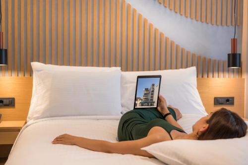 a woman laying on a bed with a laptop at Hyperion City Hotel & Spa in Chania Town