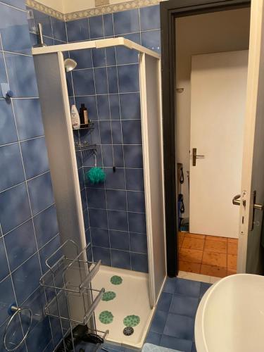 y baño con ducha de azulejos azules. en Bethel House, en Gardone Riviera