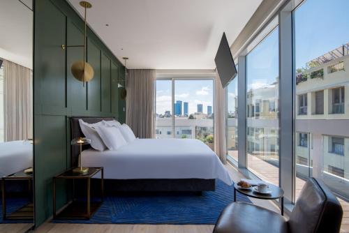 een slaapkamer met een groot bed en een groot raam bij Ink Hotel in Tel Aviv