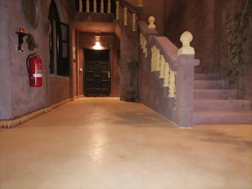 an empty hallway with a black door and stairs at Chambre d'hôtes aya in Ouzoud