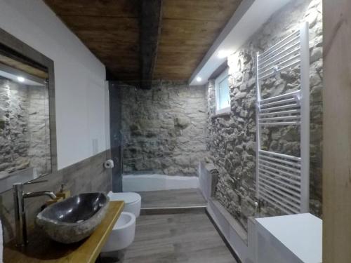 a stone bathroom with a sink and a tub at B&B La casa dei cuori in Millesimo