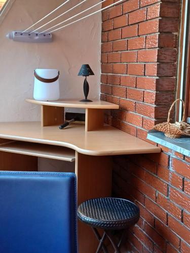 a desk against a brick wall with a blue chair at Walk Apartment in Vukovar