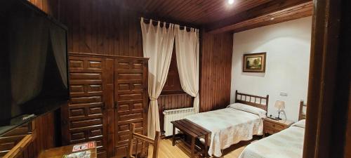 a small bedroom with two beds and a television at Hosteria Picos De Europa in Potes