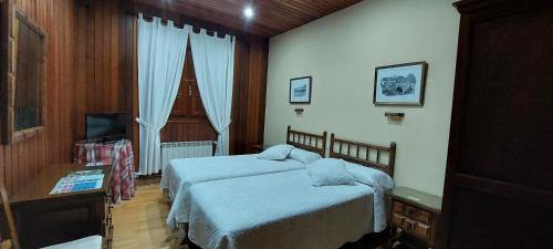 a hotel room with two beds and a television at Hosteria Picos De Europa in Potes