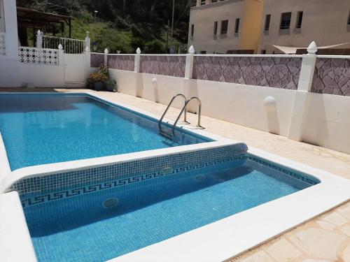 a swimming pool on the side of a house at Apartamentos Torres Cardona (Playa) in Cala Llonga