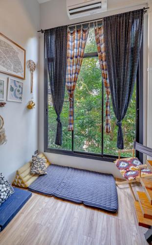 Habitación con ventana grande y alfombra azul grande. en The Yard Bangkok Hostel, en Bangkok