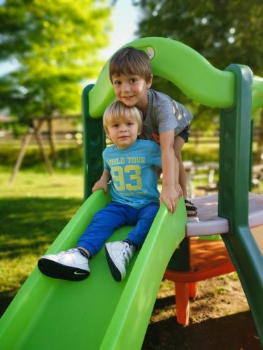 two young boys sitting on a slide at a playground at Casa Alberta in Pieve Di Ledro