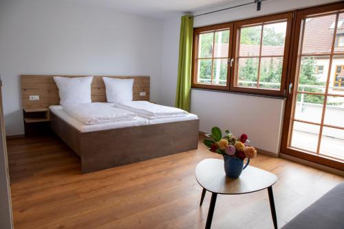 ein Schlafzimmer mit einem Bett und einem Tisch mit einer Blumenvase in der Unterkunft Gasthof Adler in Oberteuringen